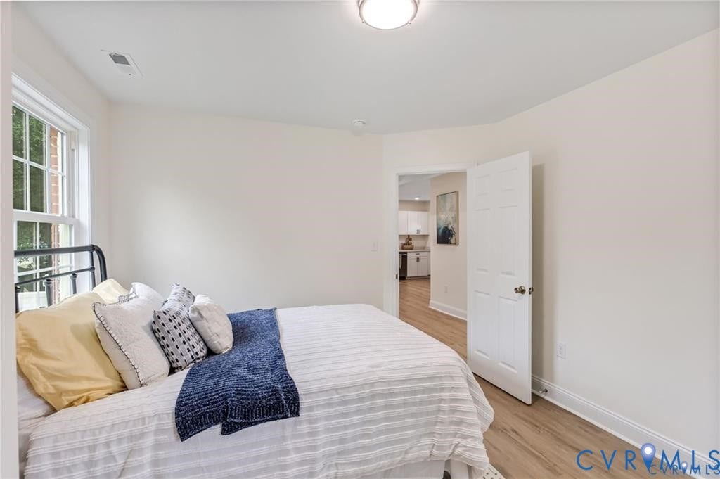 Recessed lighting, wood-finish flooring, white trim, and a window with muntins