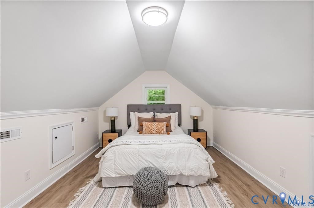 Angled ceilings with recessed lighting, wood-finish flooring, white trim, and a window