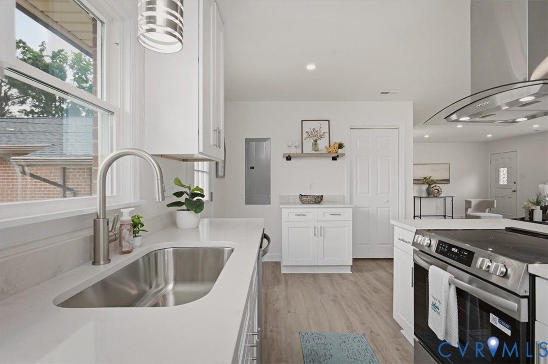 Stainless steel undermount sink with a gooseneck faucet, white cabinetry, integrated oven range with a vent hood, and wood-finish flooring