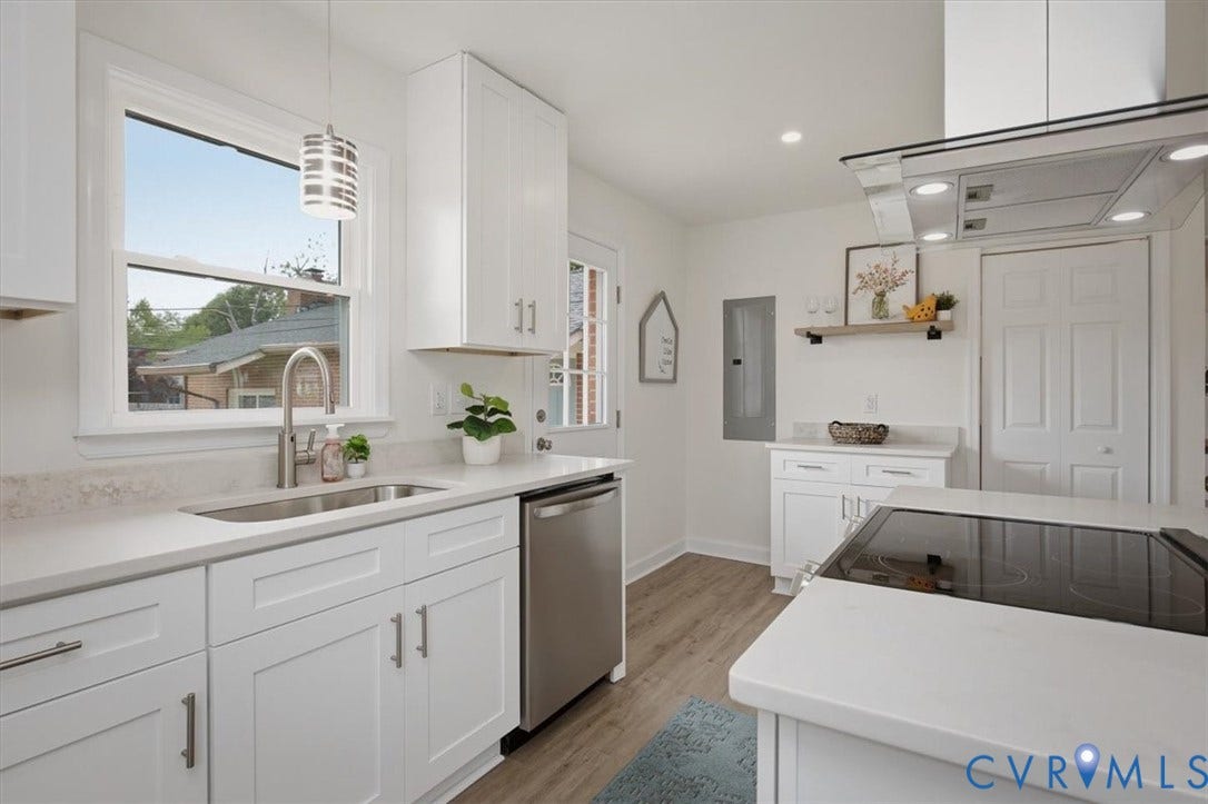 White shaker cabinetry, stainless steel appliances, wood-finish flooring, quartz countertops, and a modern range hood
