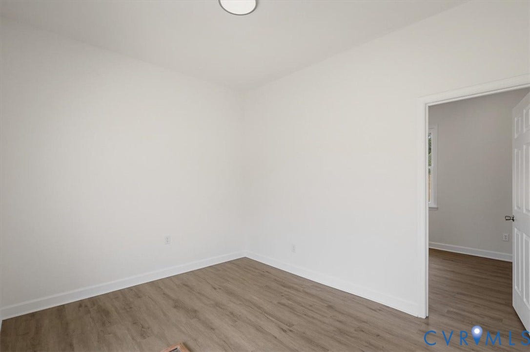 White painted walls, wood-finish flooring, and white trim