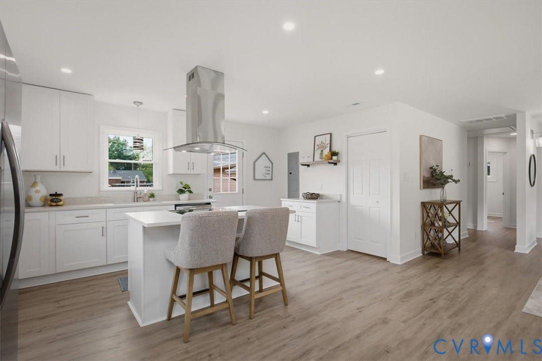Modern kitchen featuring white cabinetry, light-toned countertops, a stainless steel range hood, and recessed lighting