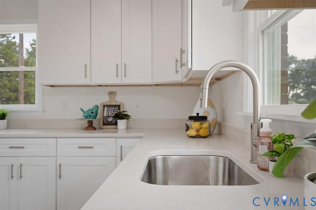 White cabinetry with brushed nickel hardware, light-toned countertops, and a stainless steel sink with a gooseneck faucet