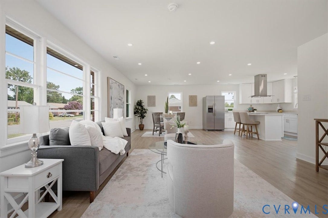 Open-concept living space featuring wood-finish flooring, recessed lighting, and large windows