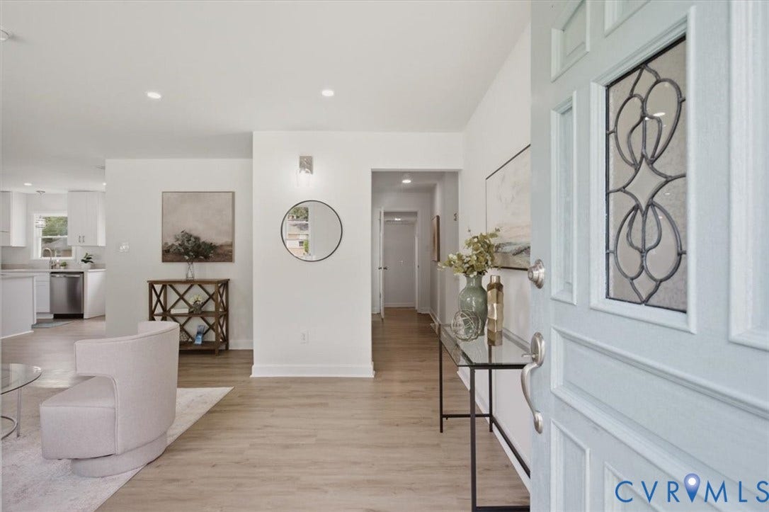 Light wood-finish flooring throughout, recessed ceiling lighting, and a front entry door with decorative glass paneling