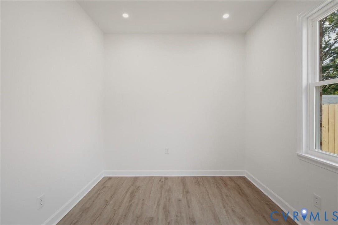 Recessed lighting, wood-finish flooring, white walls, and a white-framed window