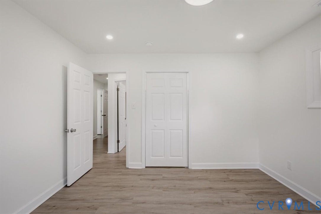 Recessed lighting, wood-finish flooring, white paneled doors, white walls, and a window