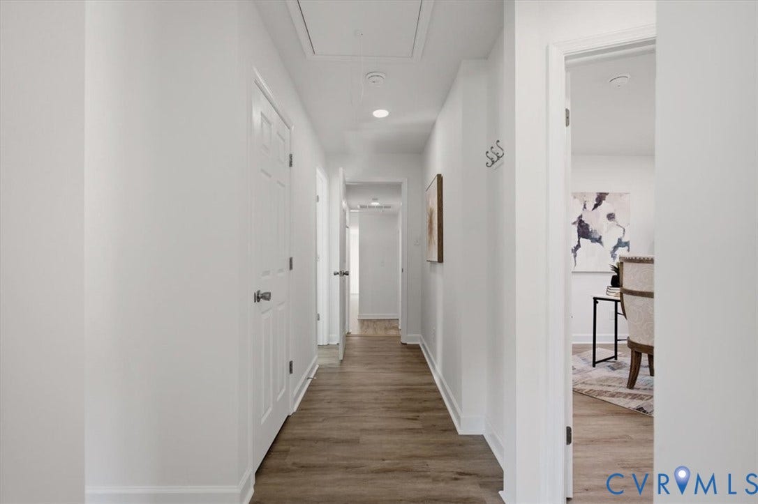 Hallway featuring wood-finish flooring, white paneled doors, recessed lighting, and crisp white walls