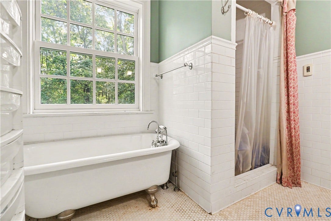 Clawfoot bathtub with a window, white subway tile walls, and a separate shower stall with white tile