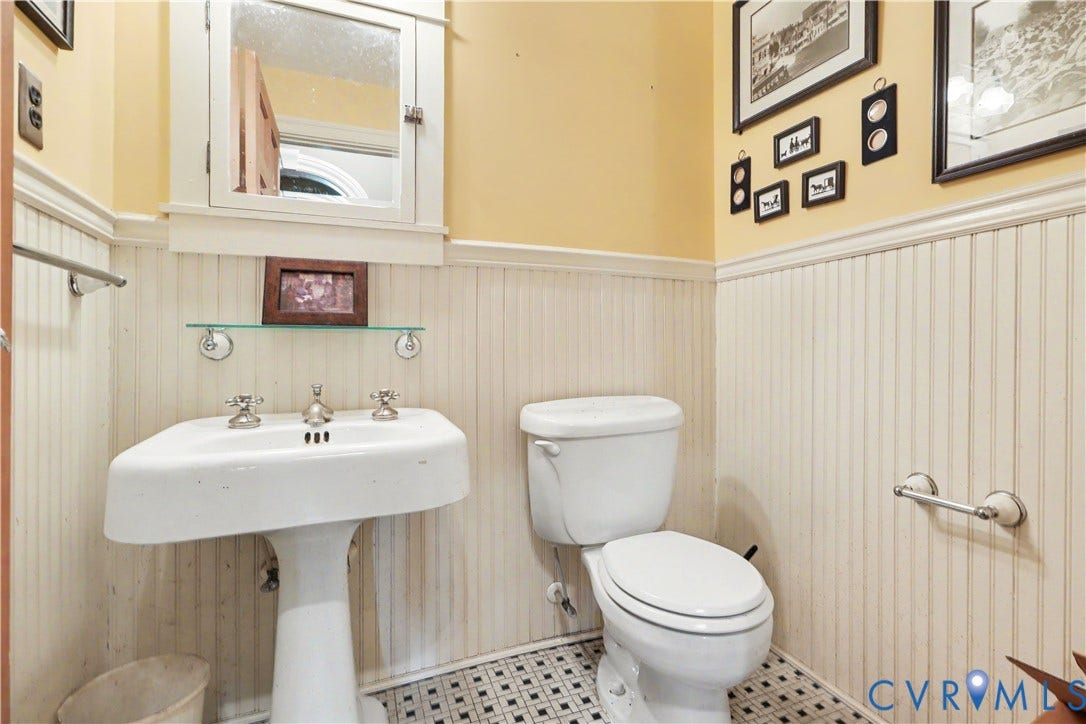 Pedestal sink with chrome fixtures, white beadboard wainscoting, wall-mounted medicine cabinet with mirror, and black and white mosaic floor tiling
