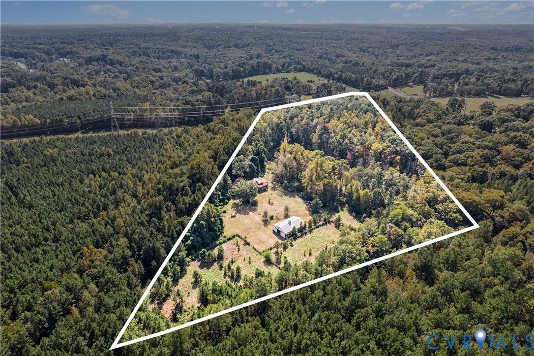 Expansive acreage featuring mature trees, open clearings, and two structures
