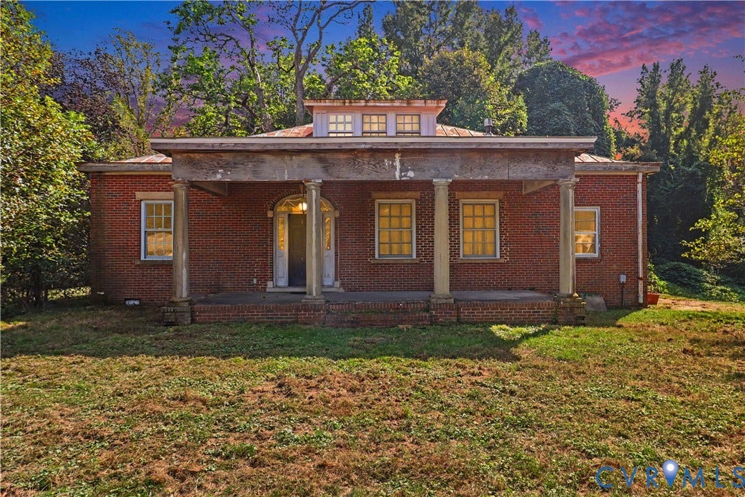 Brick exterior featuring a portico with four columns, a dormer with multiple windows, and a covered entry