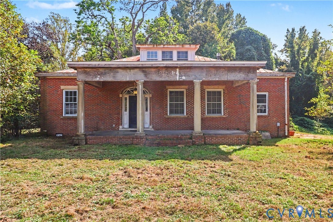 Brick exterior with a columned front porch, a dormer window, and mature surrounding trees