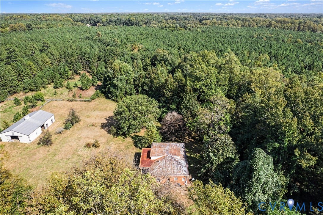 Expansive wooded acreage featuring a detached metal building and a residential structure