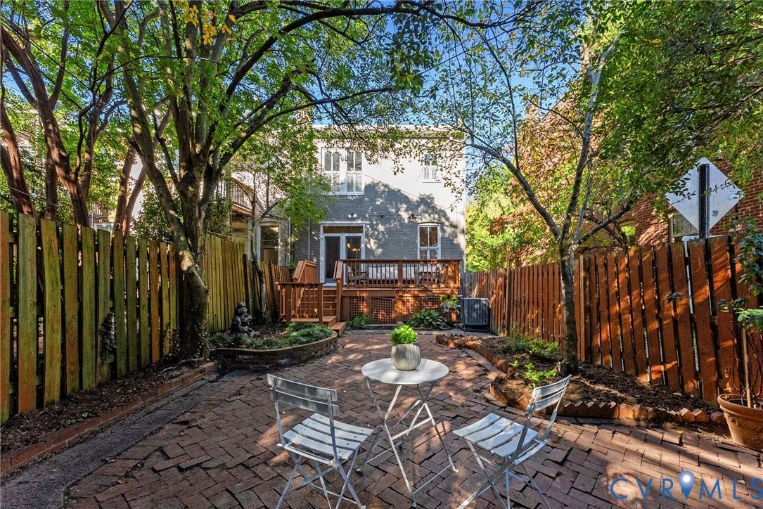 107 N Allen Avenue, The Fan, Richmond, VA 23220 Rear exterior space featuring a raised wooden deck, a herringbone-patterned brick patio, and tall wood fencing