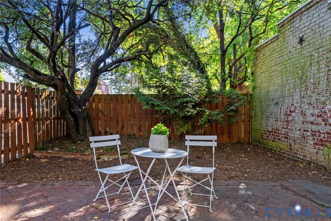 107 N Allen Avenue, The Fan, Richmond, VA 23220 Outdoor space featuring a brick patio, vertical wood fencing, mature trees, and an exposed brick exterior wall