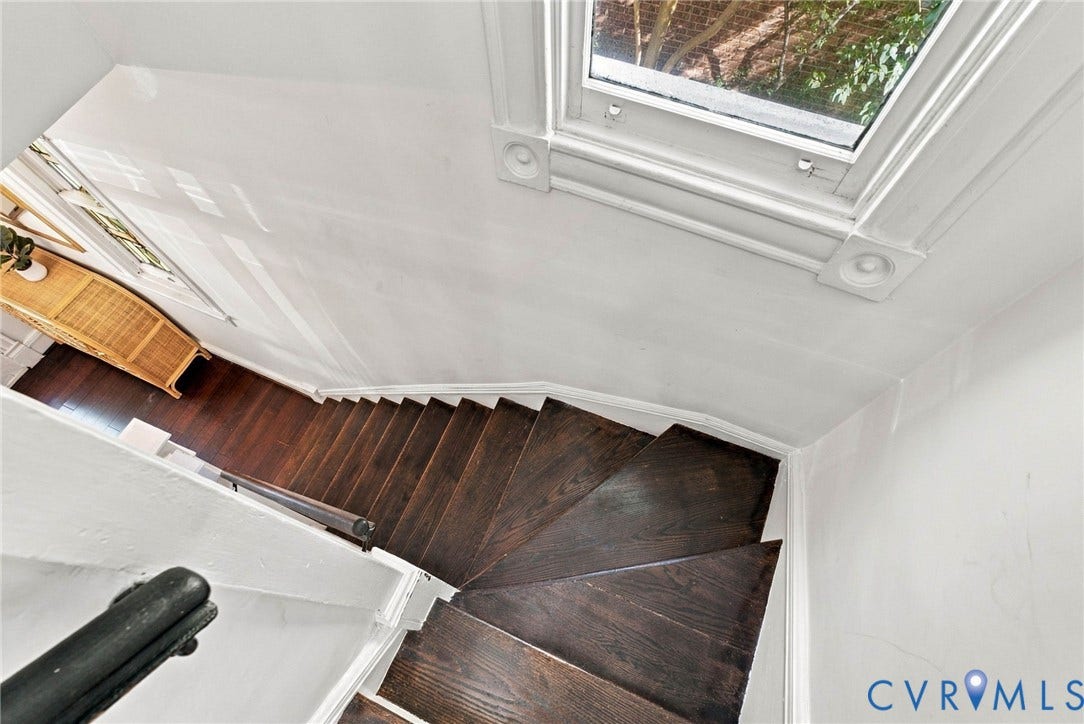 107 N Allen Avenue, The Fan, Richmond, VA 23220 Staircase featuring dark-stained wood treads, white wall paneling, detailed window casing with rosette corner blocks, and a simple dark railing