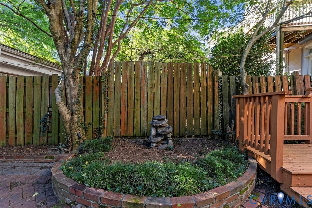 107 N Allen Avenue, The Fan, Richmond, VA 23220 Rear yard featuring a wood-plank privacy fence, brick-bordered planter bed, wood-finish decking, and mature trees