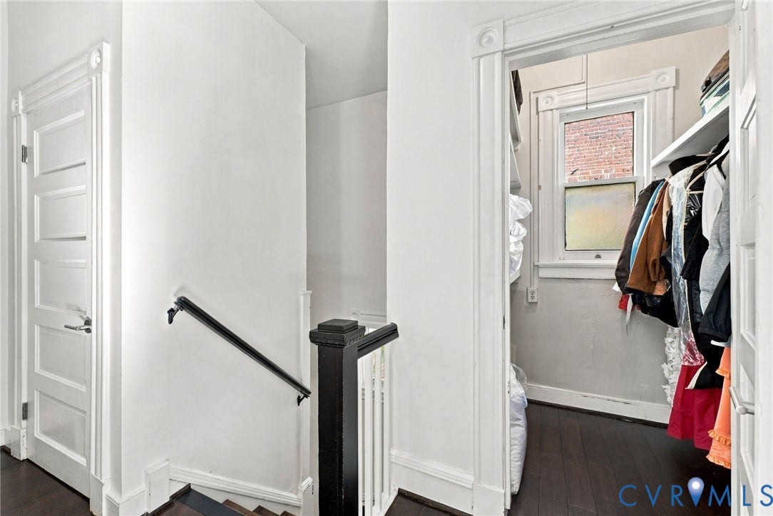 107 N Allen Avenue, The Fan, Richmond, VA 23220 Five-panel interior doors with classic casing, dark wood-finish flooring, staircase with a custom-painted black handrail and newel post, and walk-in storage area with built-in shelving and a window