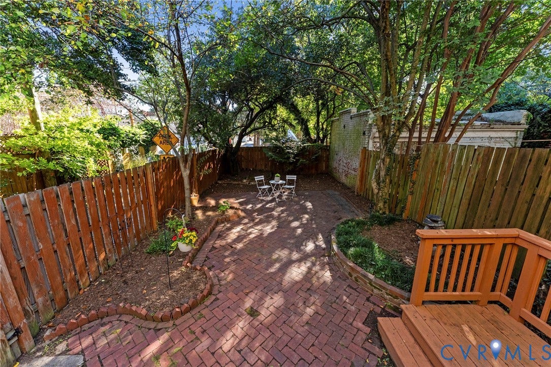 107 N Allen Avenue, The Fan, Richmond, VA 23220 Private courtyard featuring brick herringbone paving, wood privacy fencing, mature trees, and tiered wood decking