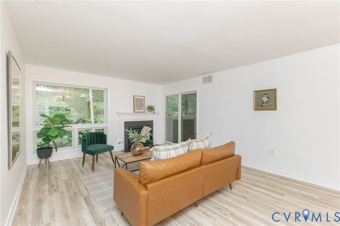 10404 Iron Mill Road, Chesterfield, VA 23235 Spacious living area featuring wood-finish flooring, a fireplace with a white mantel, and large windows