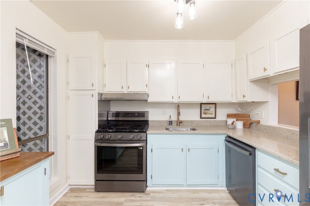 10404 Iron Mill Road, Chesterfield, VA 23235 Kitchen featuring light wood-finish flooring, white upper cabinetry, light blue lower cabinetry, stainless steel appliances, and quartz countertops.