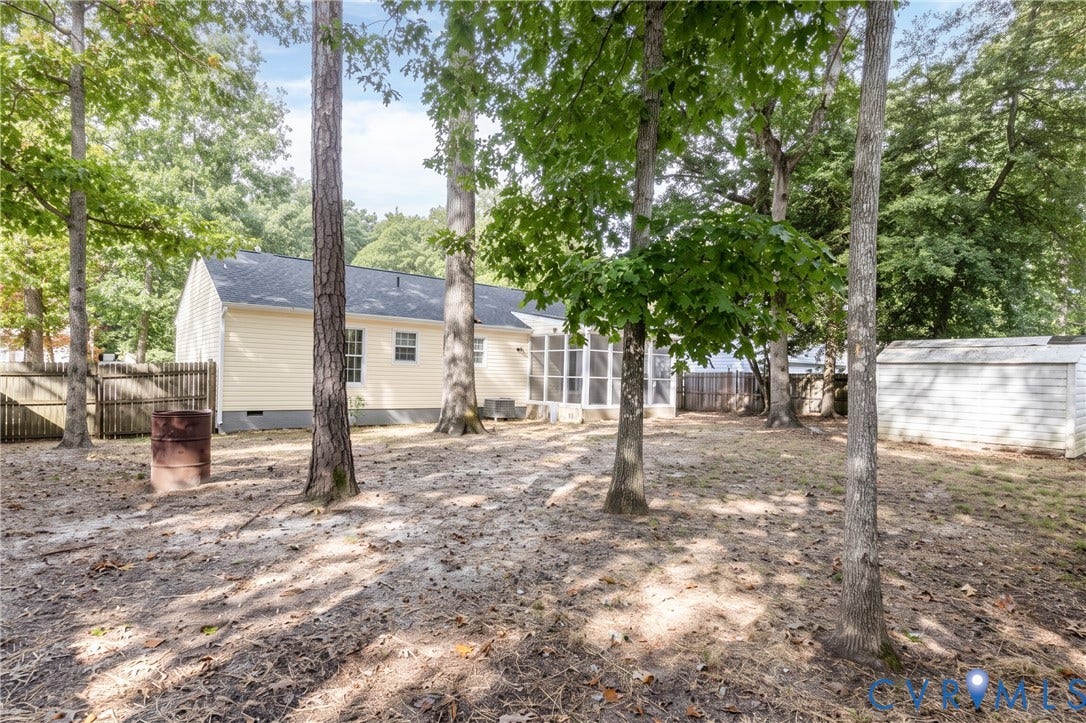 Expansive backyard featuring mature trees, a screened-in porch, and a storage shed
