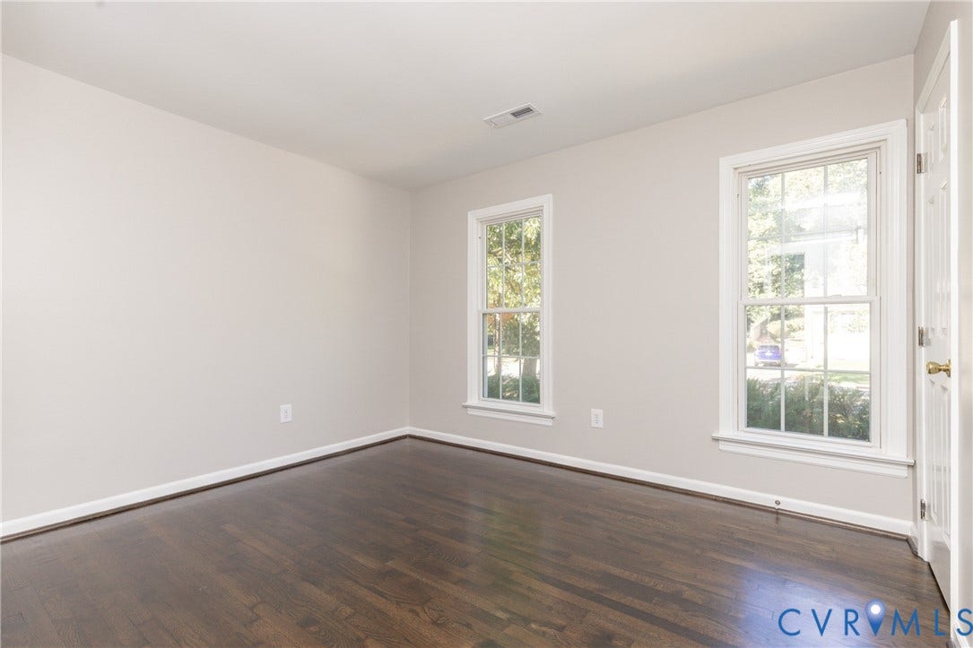 Hardwood flooring, painted walls, white trim, and two double-hung windows