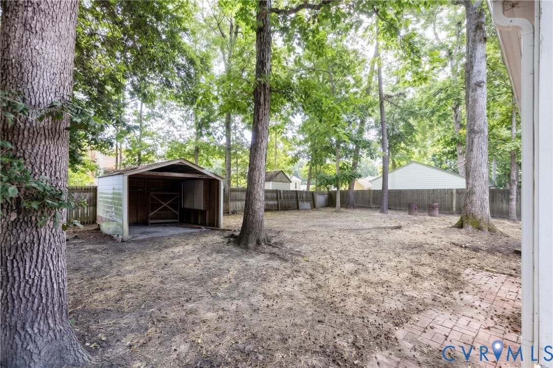 Spacious lot featuring mature trees, a detached storage shed, privacy fencing, and a brick paver patio