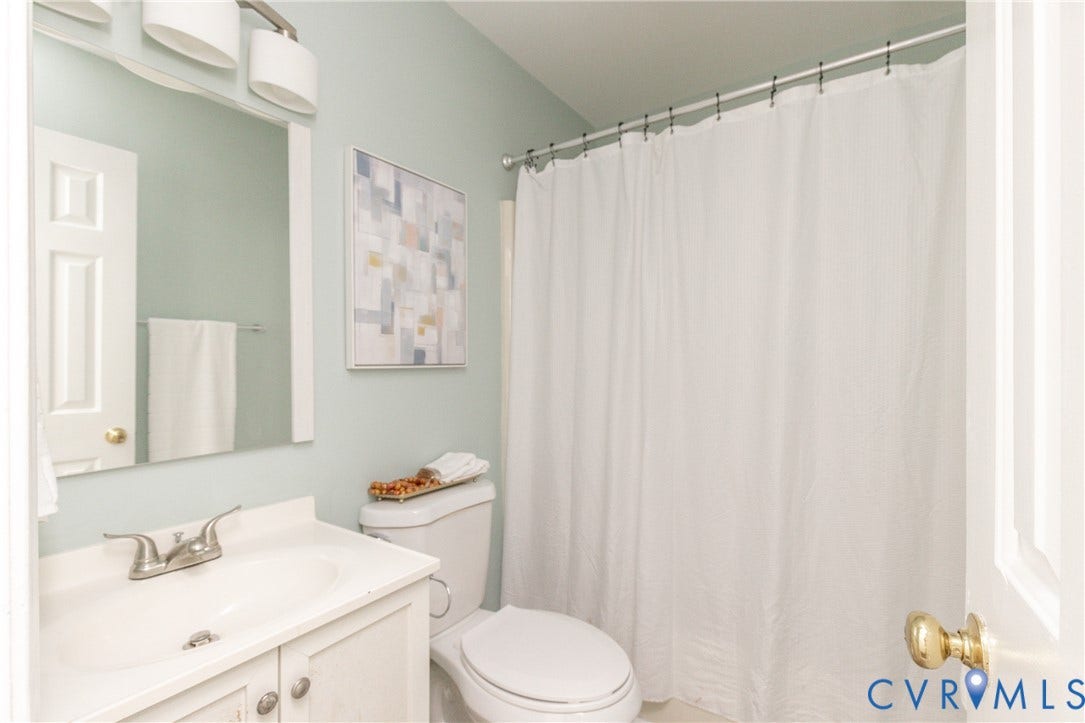 White vanity with an integrated sink, brushed nickel faucet, wall-mounted mirror, and overhead vanity lighting