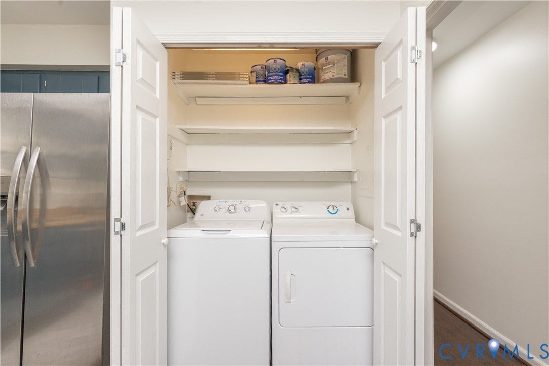 Built-in laundry closet with bifold doors, integrated shelving, and white washer and dryer units