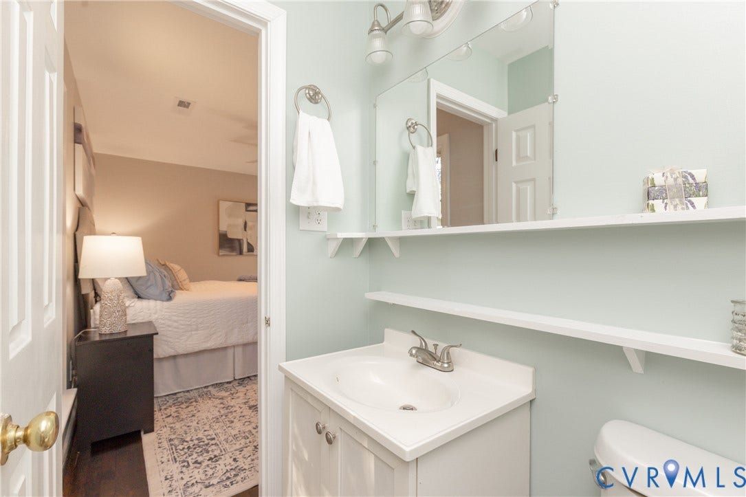 Bathroom vanity with a white countertop and integrated sink, chrome faucet, and white cabinetry