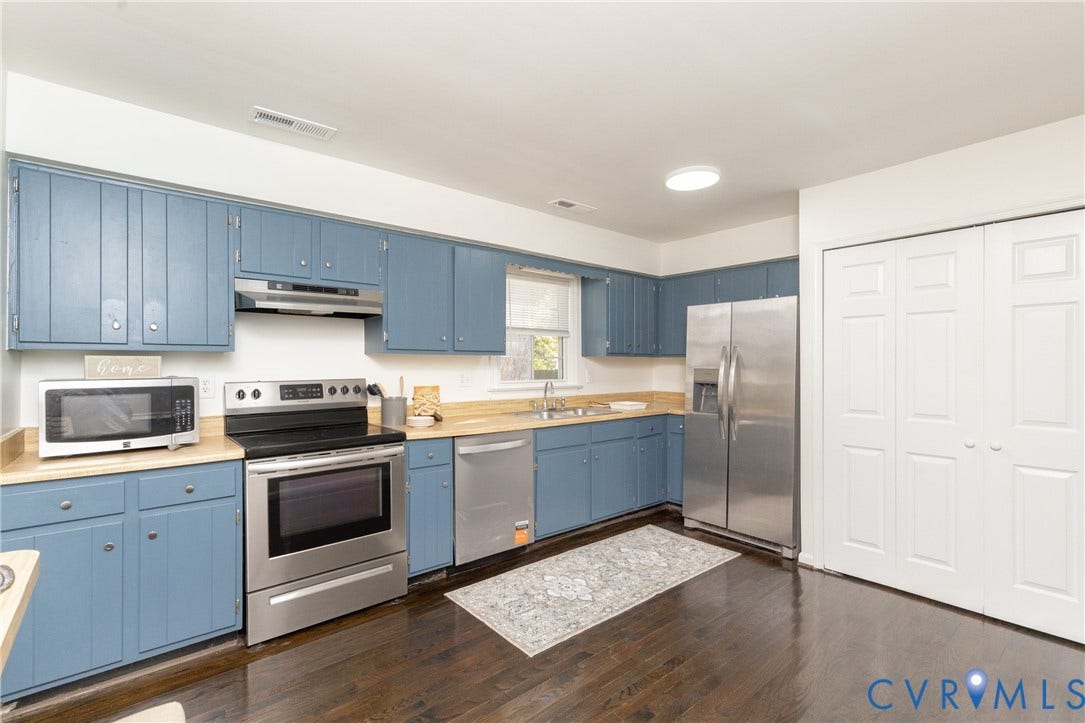 Kitchen featuring wood-finish flooring, blue cabinetry, stainless steel appliances, and a double-door pantry