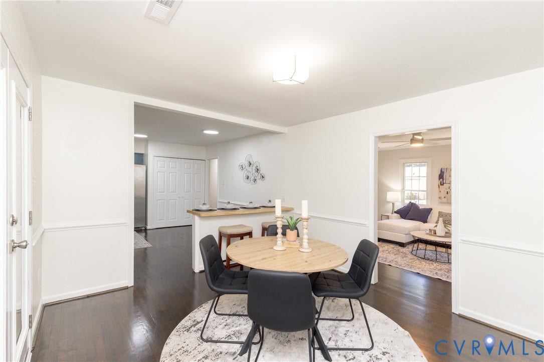 Hardwood flooring, white walls, chair rail molding, ceiling light fixture, and a breakfast bar with seating