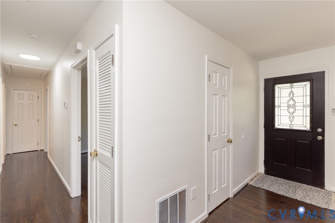 Dark wood-finish flooring, white paneled doors, and a decorative glass front door