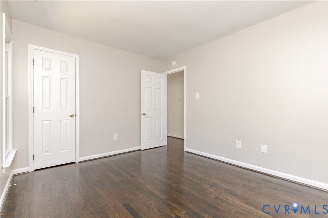 Wood-finish flooring, light neutral wall color, white trim, and white paneled doors