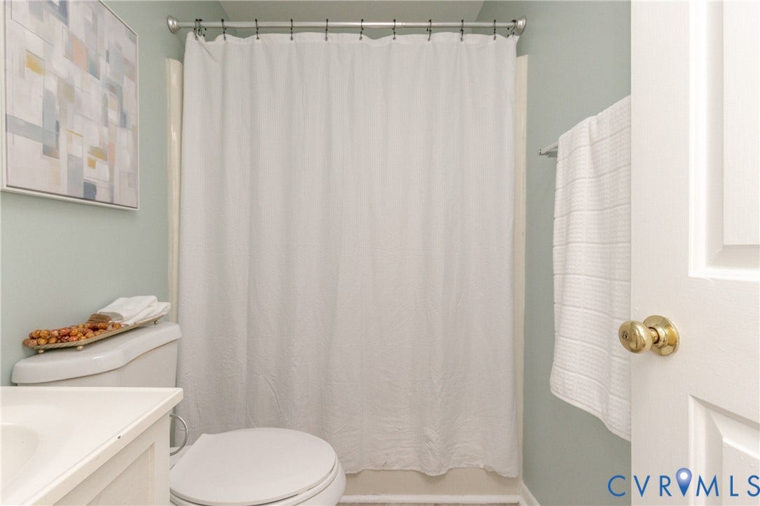 White shower curtain and rod, toilet, and light-colored walls