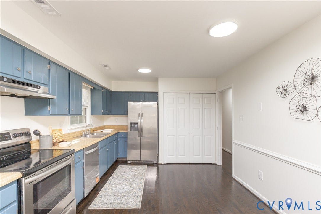 Kitchen featuring wood-finish flooring, blue cabinetry, stainless steel appliances, and ceiling-mounted lighting