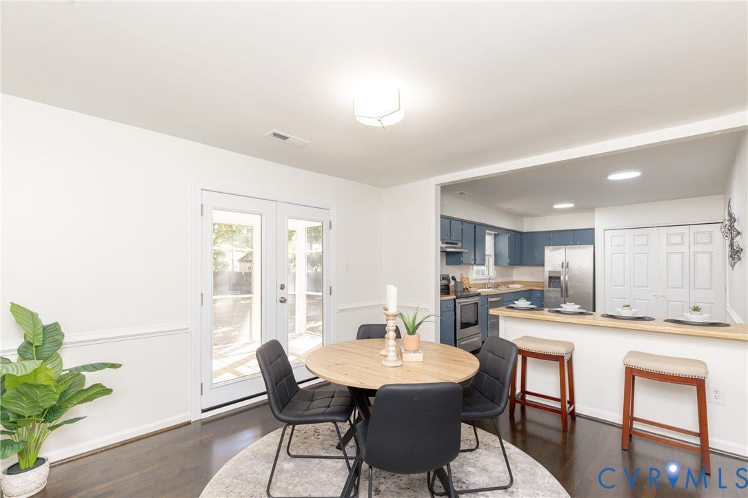 Dining area with dark wood-finish flooring, white walls, and wainscoting