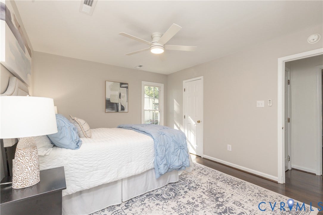 Dark wood-finish flooring, white ceiling fan, light neutral wall paint, white trim, and a white paneled door