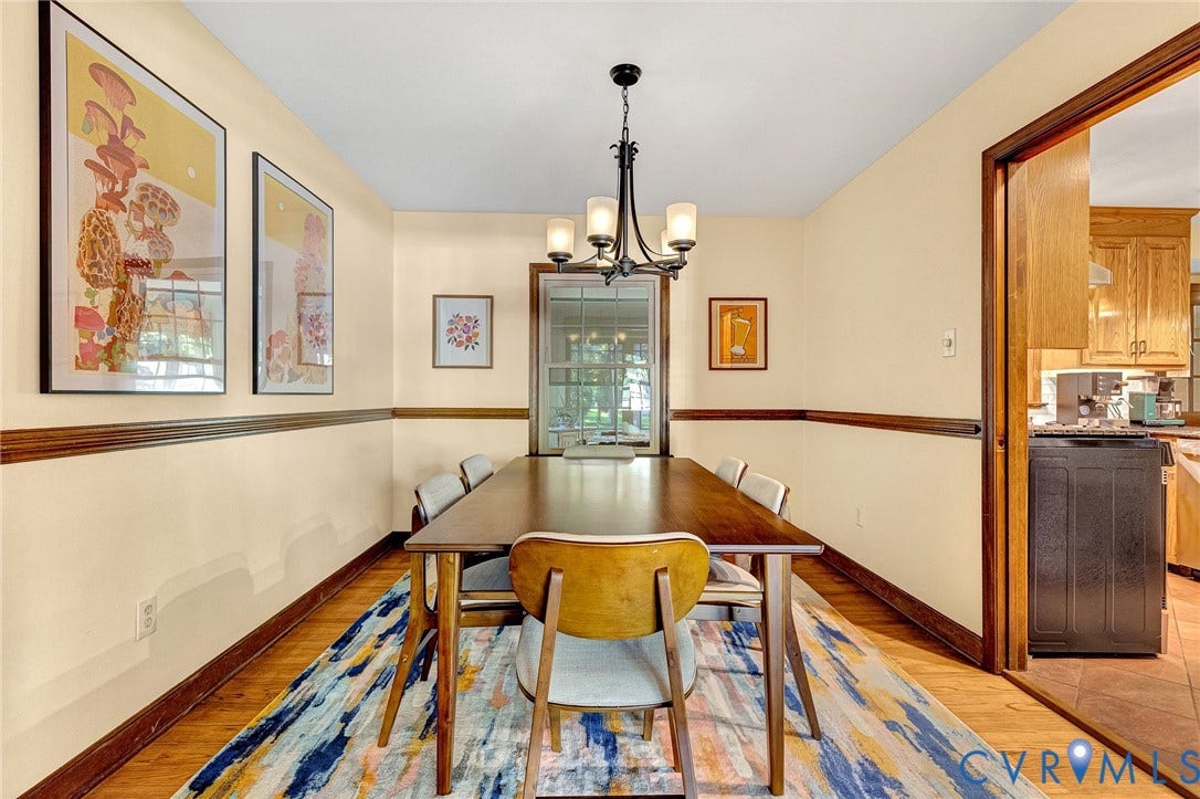 11410 Driscoll Road, Chester, VA 23831 Dining space featuring wood-finish flooring, dark wood chair rail molding, a multi-arm metal chandelier, and a single-hung window with muntins