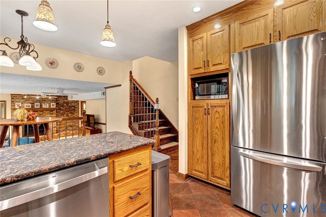 11410 Driscoll Road, Chester, VA 23831 Kitchen area featuring floor-to-ceiling wood cabinetry, stainless steel appliances, stone-finish countertops, tile flooring, and decorative hanging light fixtures