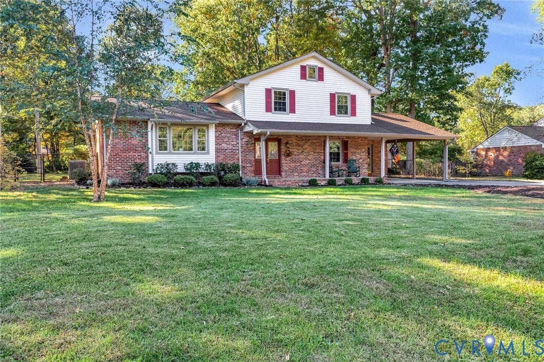 11410 Driscoll Road, Chester, VA 23831 Two-story residence featuring a brick and white siding exterior, covered front porch, attached carport, and mature landscaping