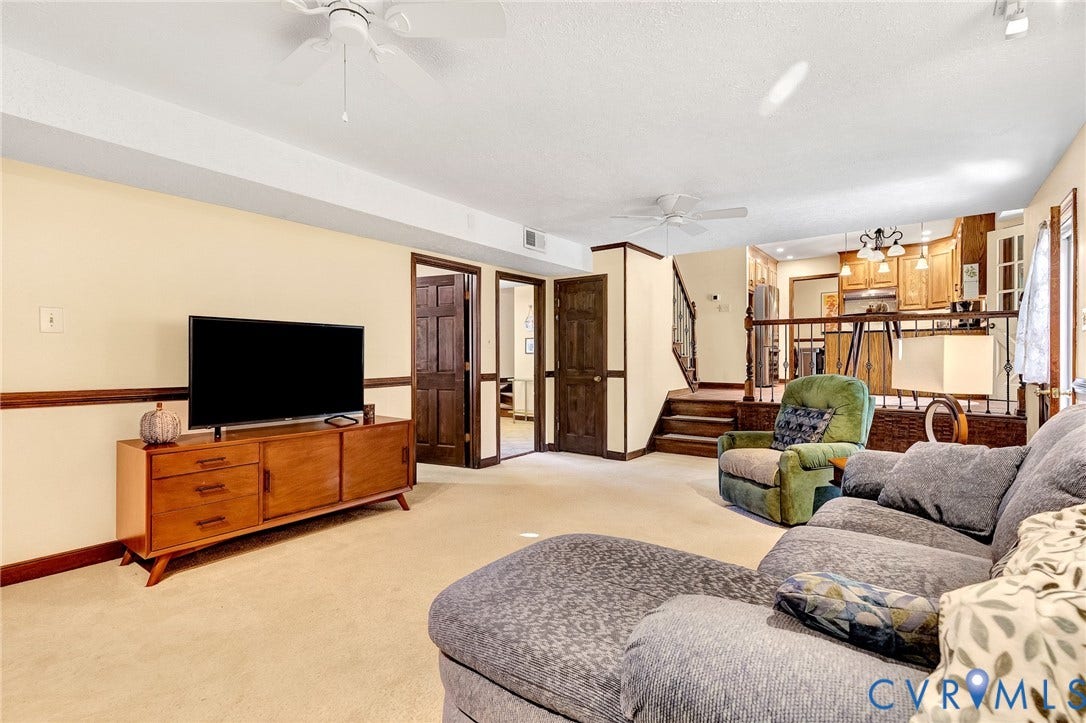 11410 Driscoll Road, Chester, VA 23831 Spacious interior featuring neutral carpeting, multi-panel wood doors, chair rail molding, and a tiered layout with decorative wood railing