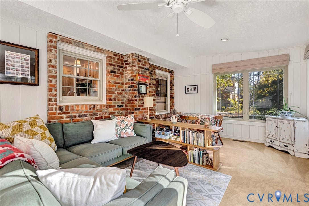 11410 Driscoll Road, Chester, VA 23831 Interior space featuring an exposed brick accent wall, large picture windows, vertical wall paneling, and a ceiling-mounted fan