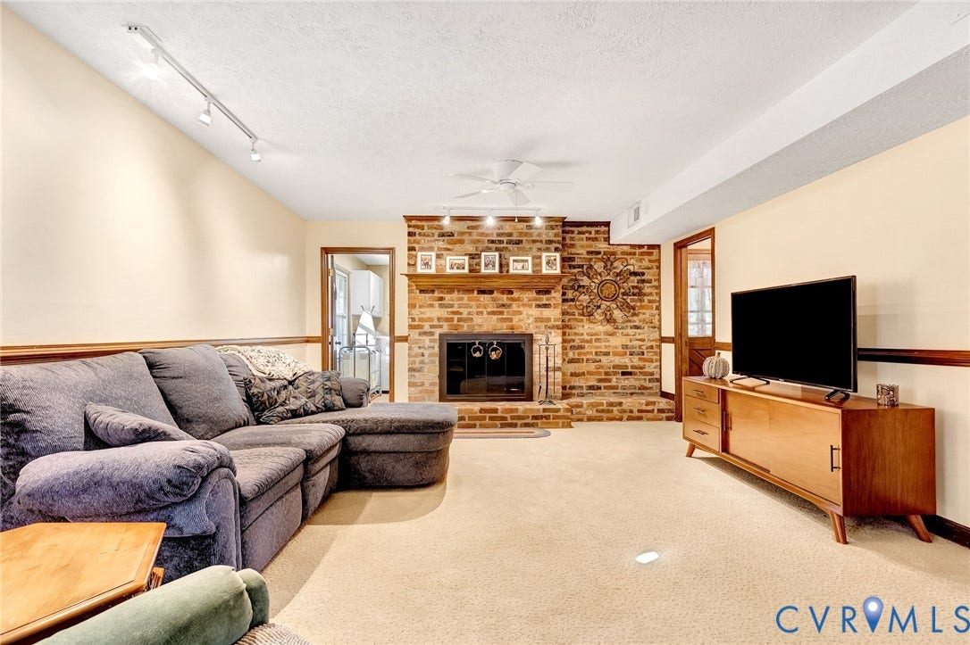 11410 Driscoll Road, Chester, VA 23831 Full-height brick fireplace featuring a wood mantel, raised hearth, and track lighting, complemented by chair rail molding