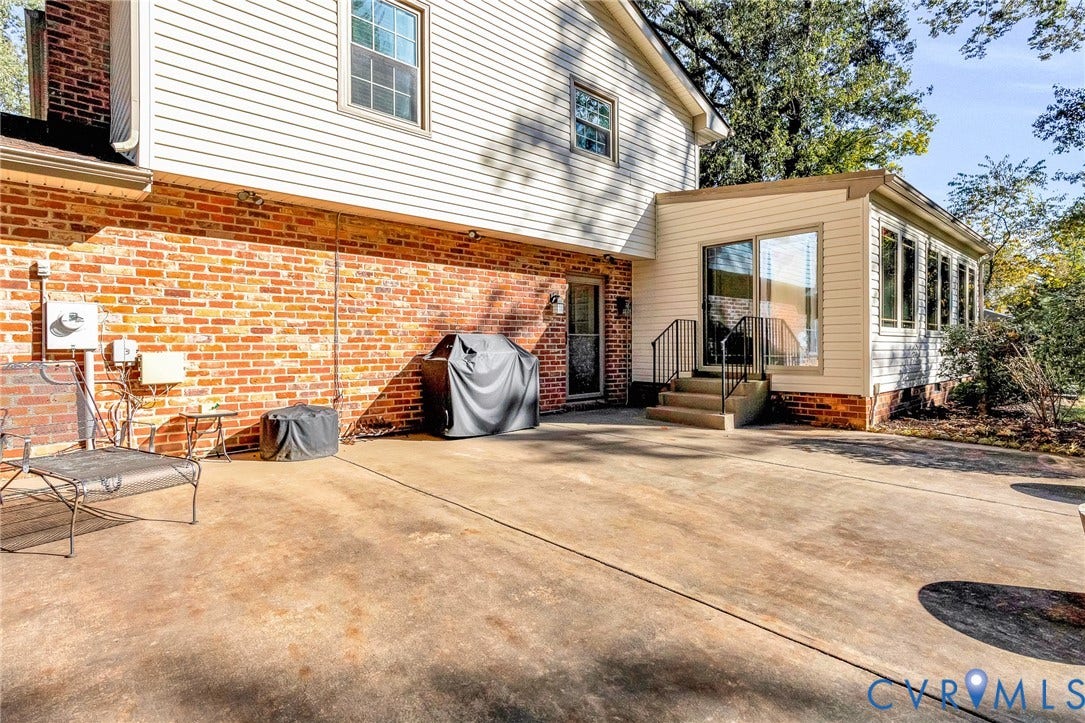 11410 Driscoll Road, Chester, VA 23831 Exterior facade featuring a combination of red brick and horizontal siding, concrete patio, sliding glass door, and metal handrails