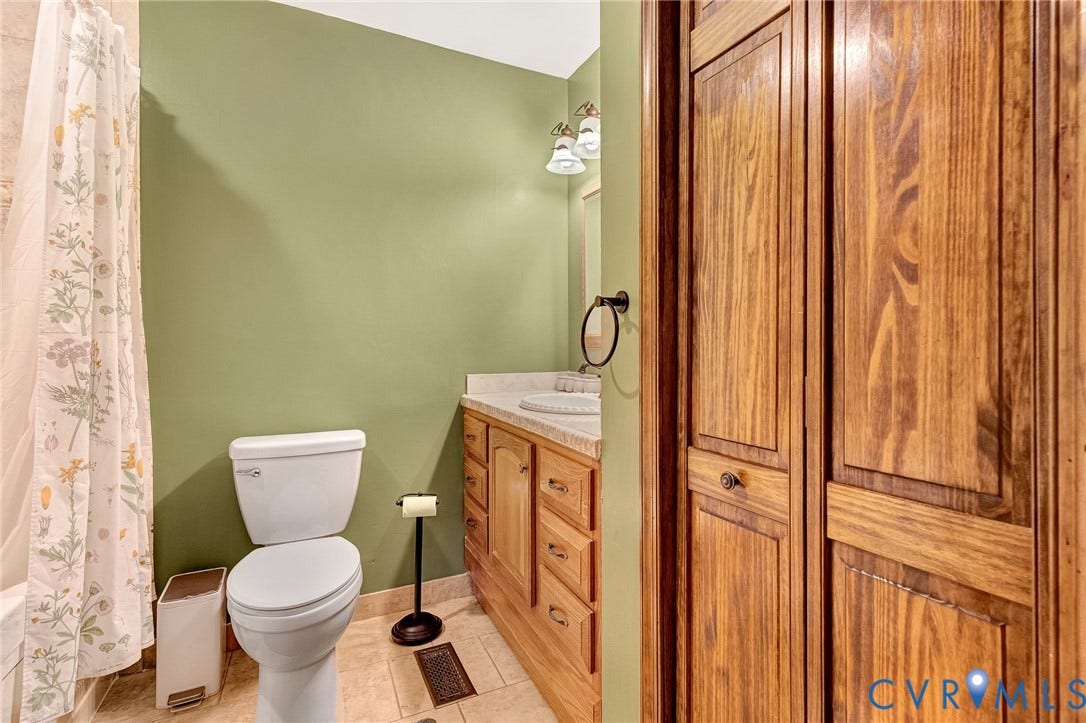 11410 Driscoll Road, Chester, VA 23831 Bathroom featuring wood-finish cabinetry, stone-patterned countertop, tile flooring, and bi-fold wooden closet doors
