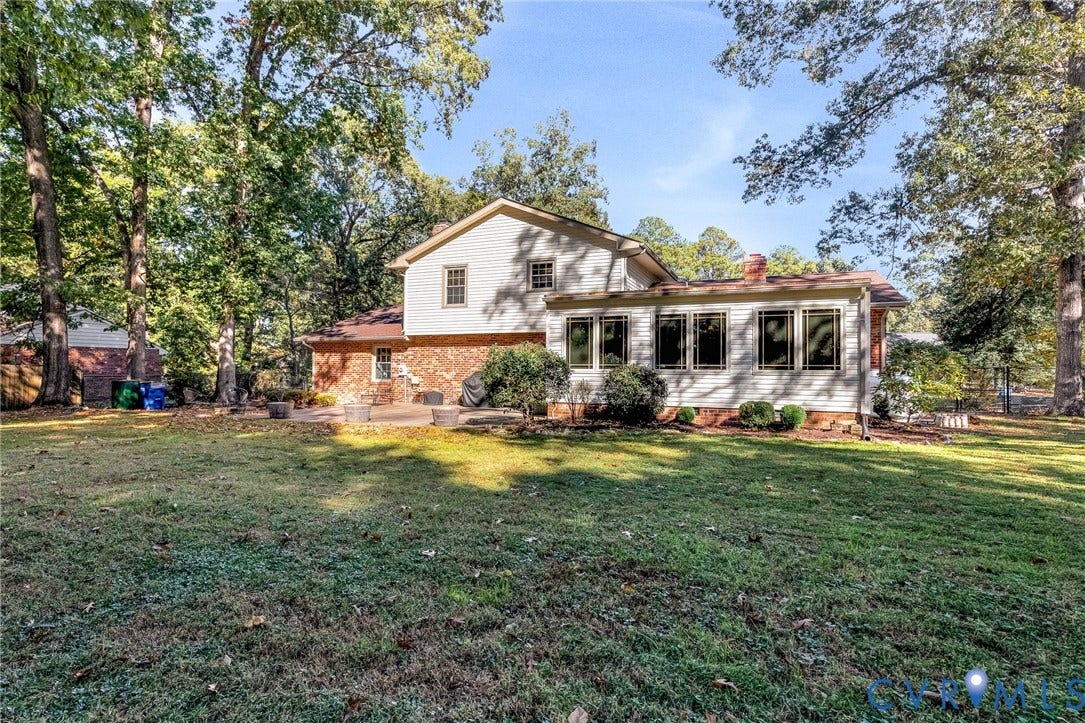 11410 Driscoll Road, Chester, VA 23831 Expansive backyard featuring a manicured lawn, mature trees, multi-tone brick and horizontal siding exterior, and a stone-paver patio