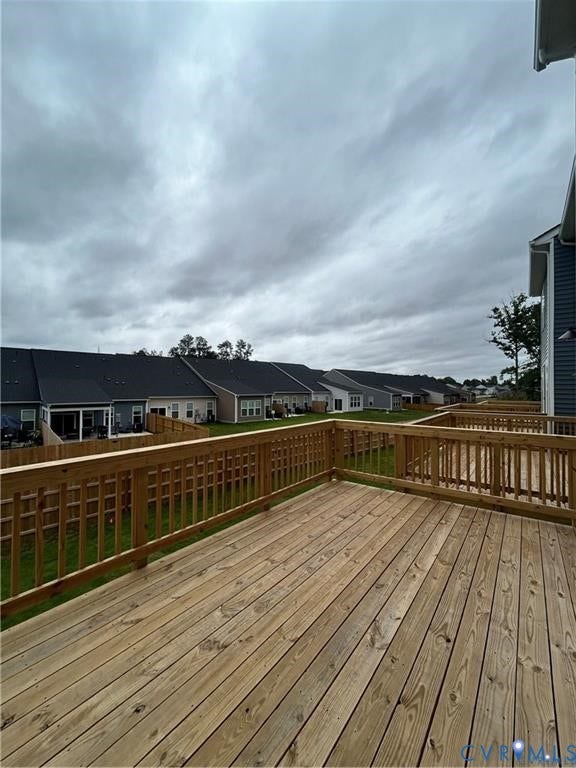 Spacious wooden deck with wooden railings, featuring a manicured lawn
